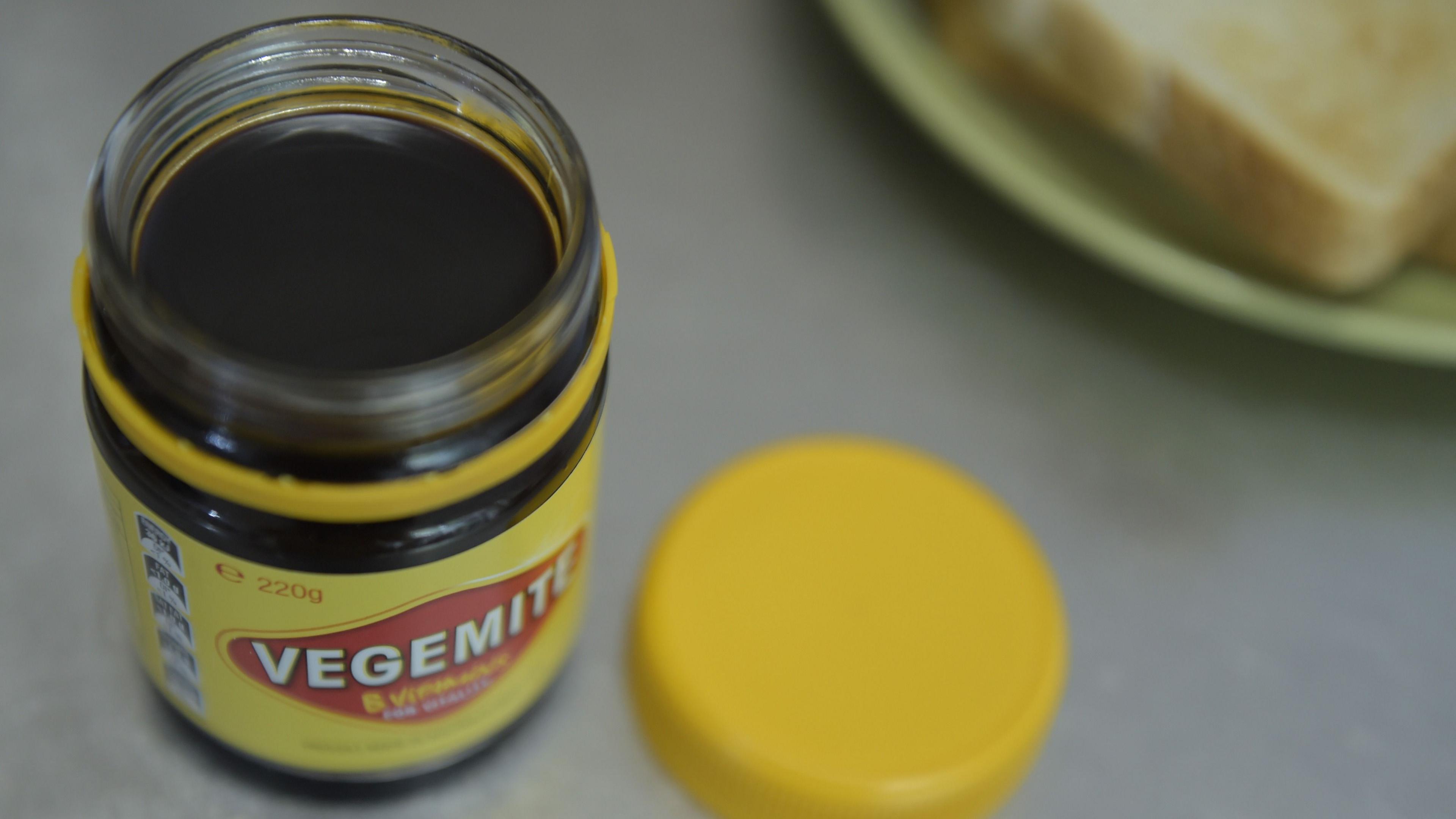 A jar of Vegemite on a table with toast