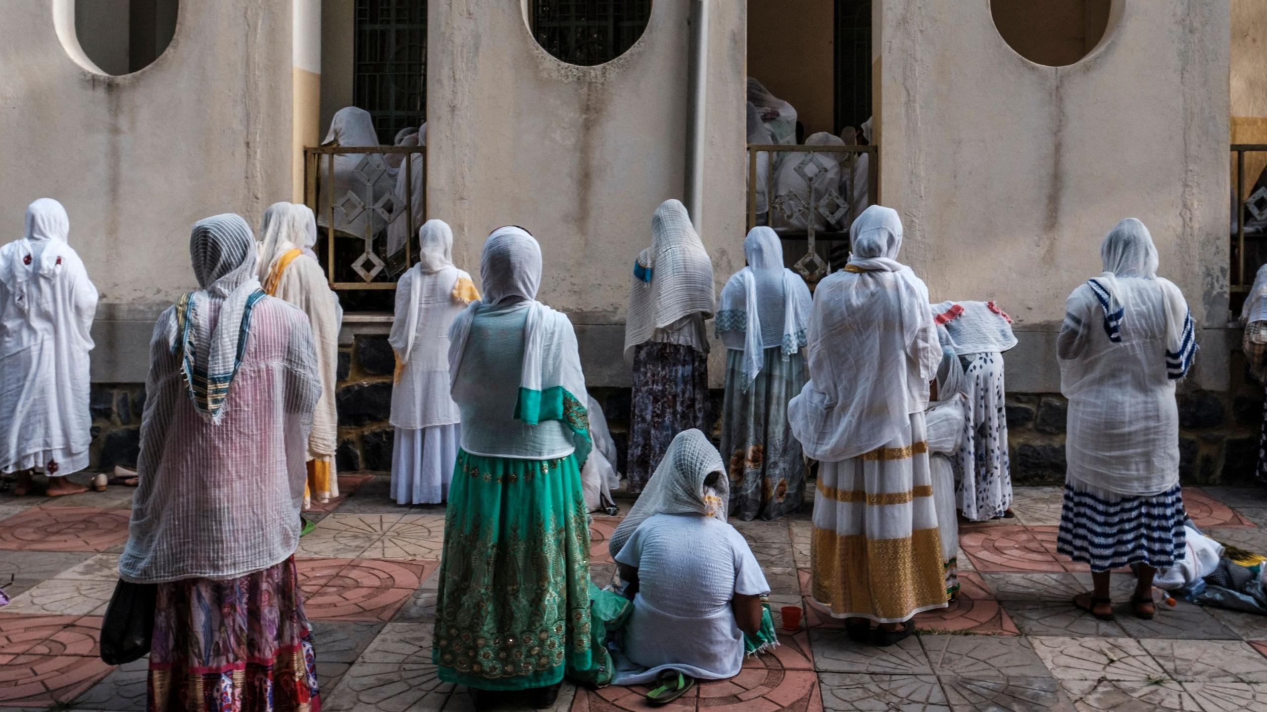 Women wearing traditional Ethiopian dresses prayer outside a church