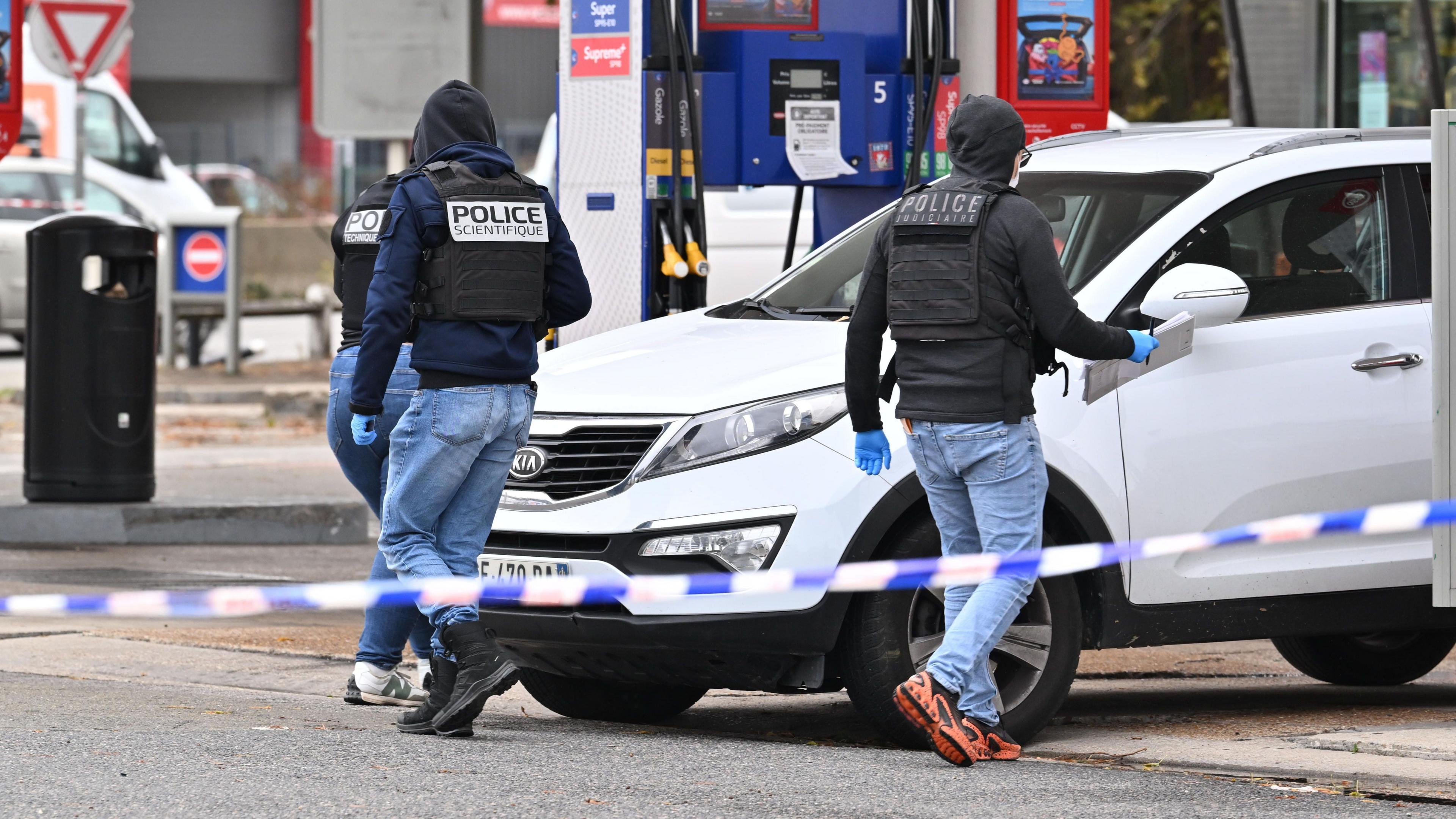 Forensic officers examine evidence at a petrol station where a gunman opened fire from a vehicle.